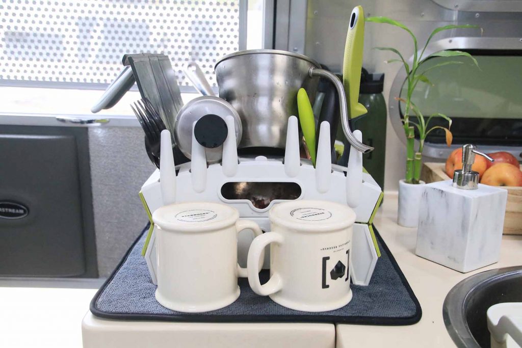 A collapsable drying rack with various plates and cups drying.