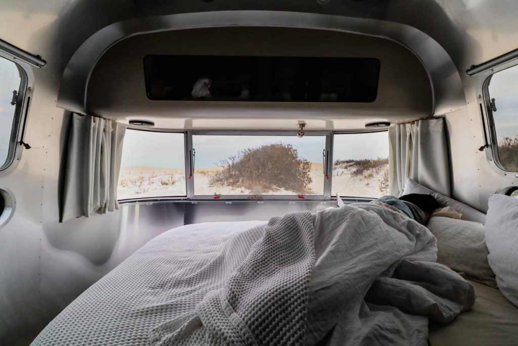 A person sleeps in the bed of an Airstream trailer.