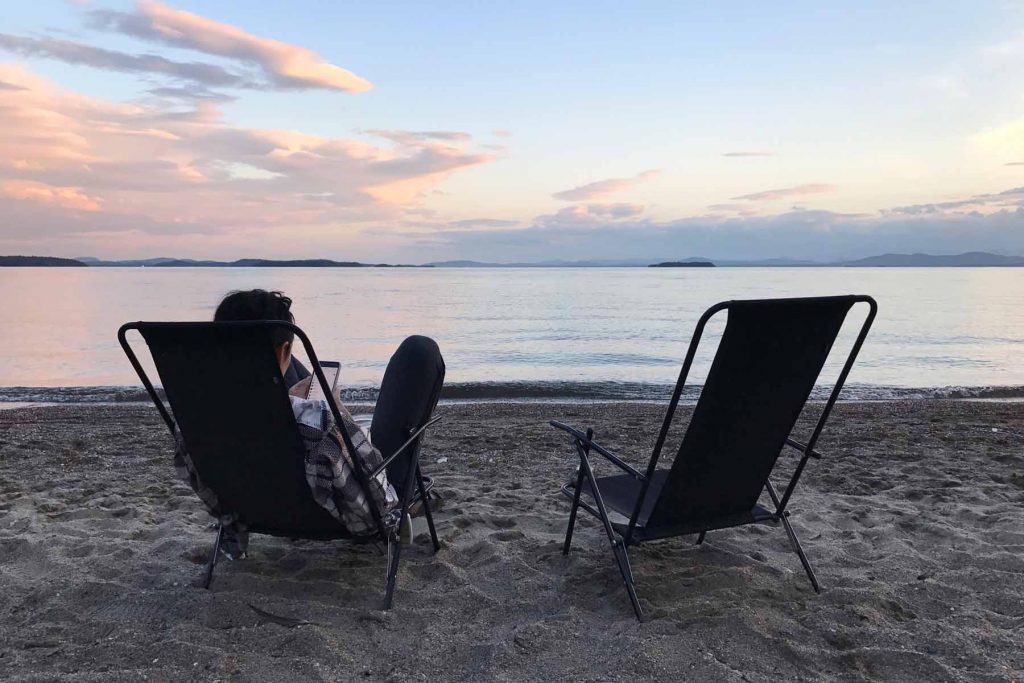 A woman sits on camp chairs looking out to Lake Champlain in Vermont.