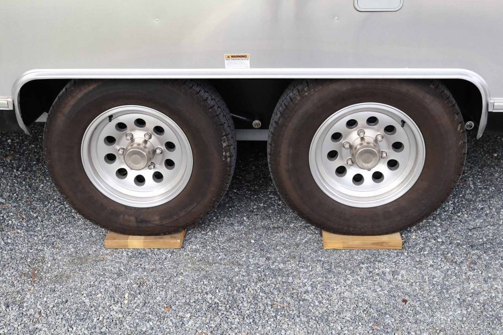 Tires of an RV on top of two wooden planks acting as levels.