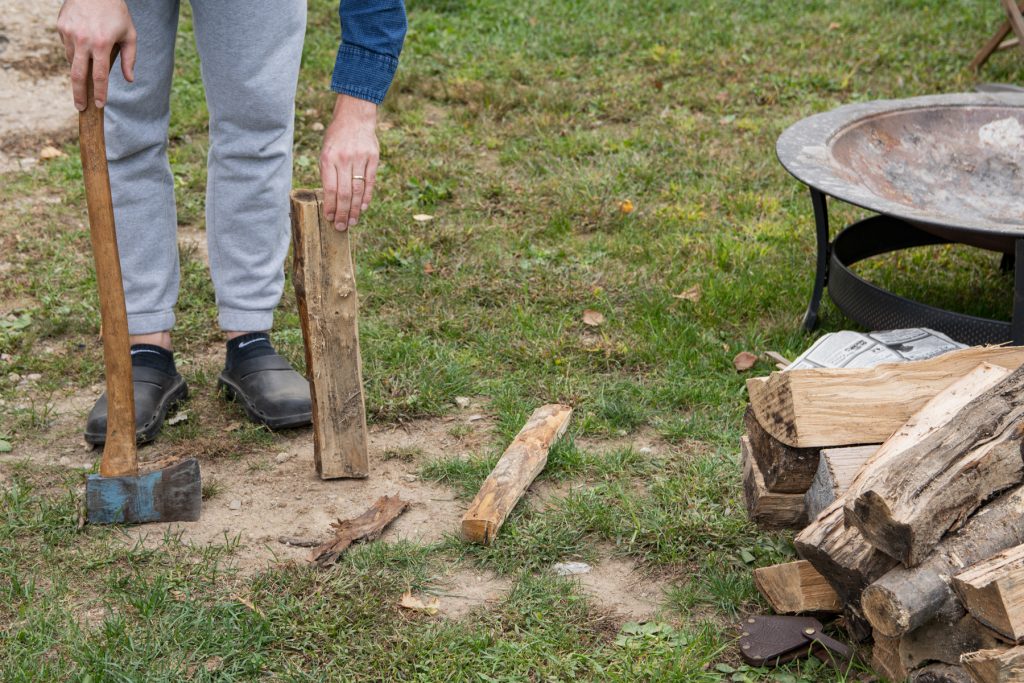 A man prepares to split a piece of firewood by propping it up.