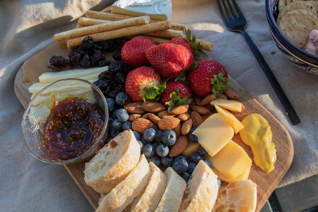 A closeup of a platter filled with bread, nuts, and cheeses along with some berries.