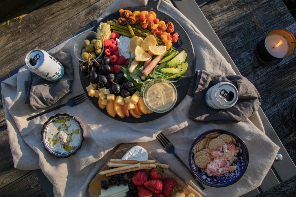 A birds-eye view of Crate & Barrel's Table In A Bag with cans of beer, and platters of cheese and charcuterie.