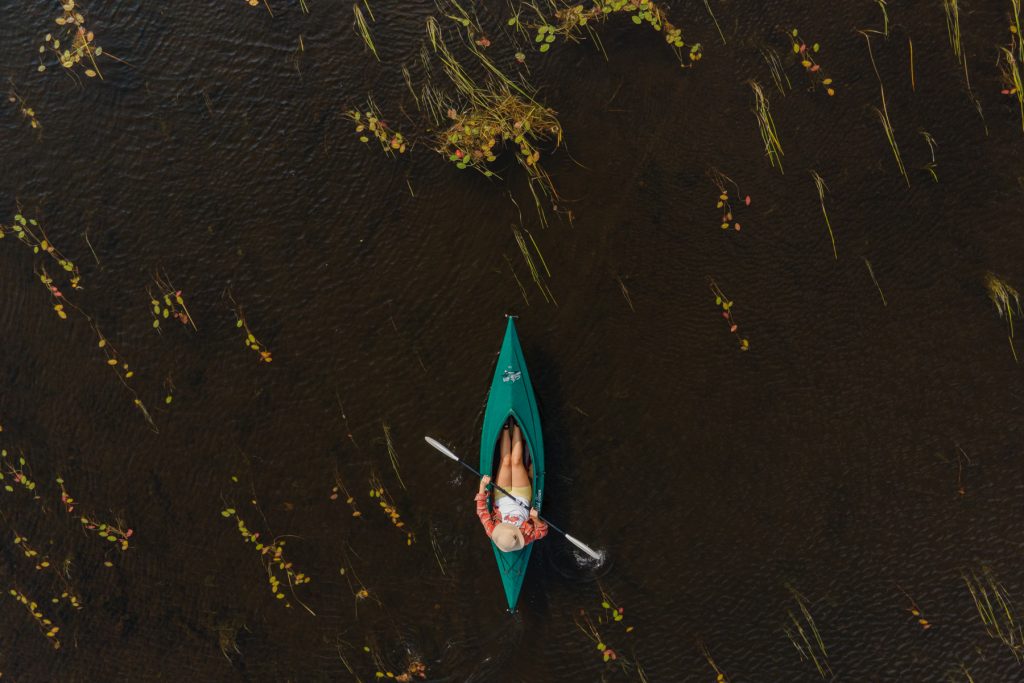 A woman paddles in a green kayak in Junior Lake in Lakeville, Maine.