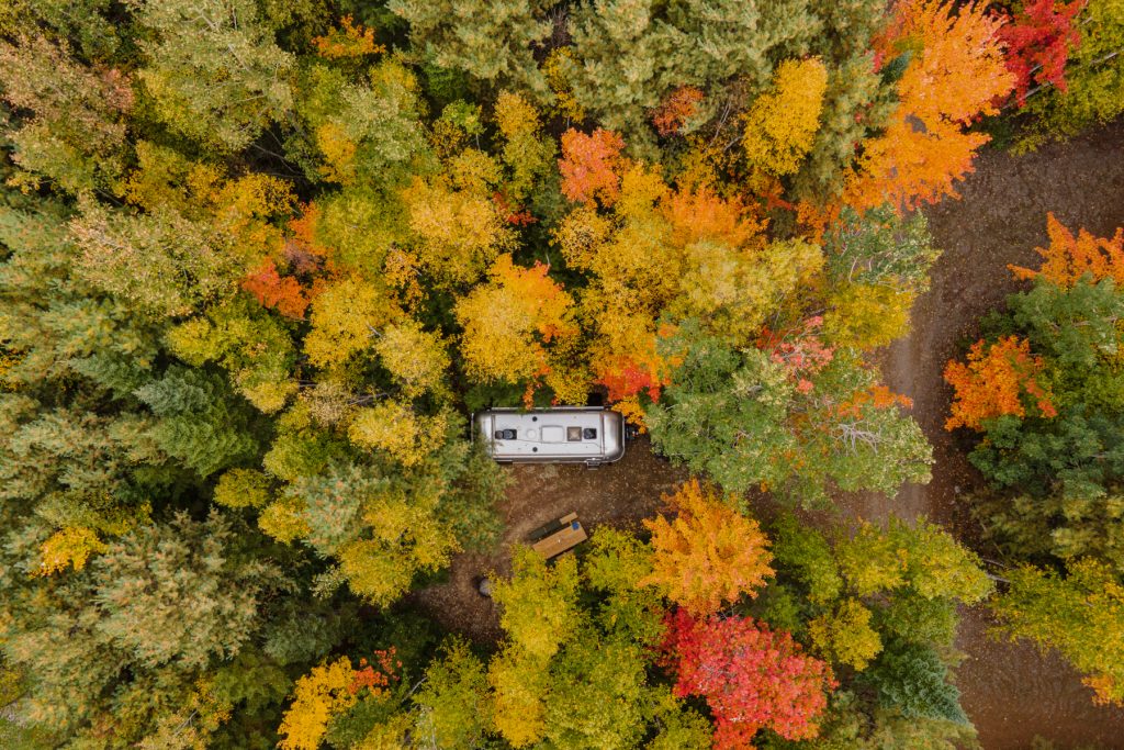 Autumn of fall foliage surrounding an Airstream at Wild Fox Cabins and Campgrounds in Lakeville, Maine.