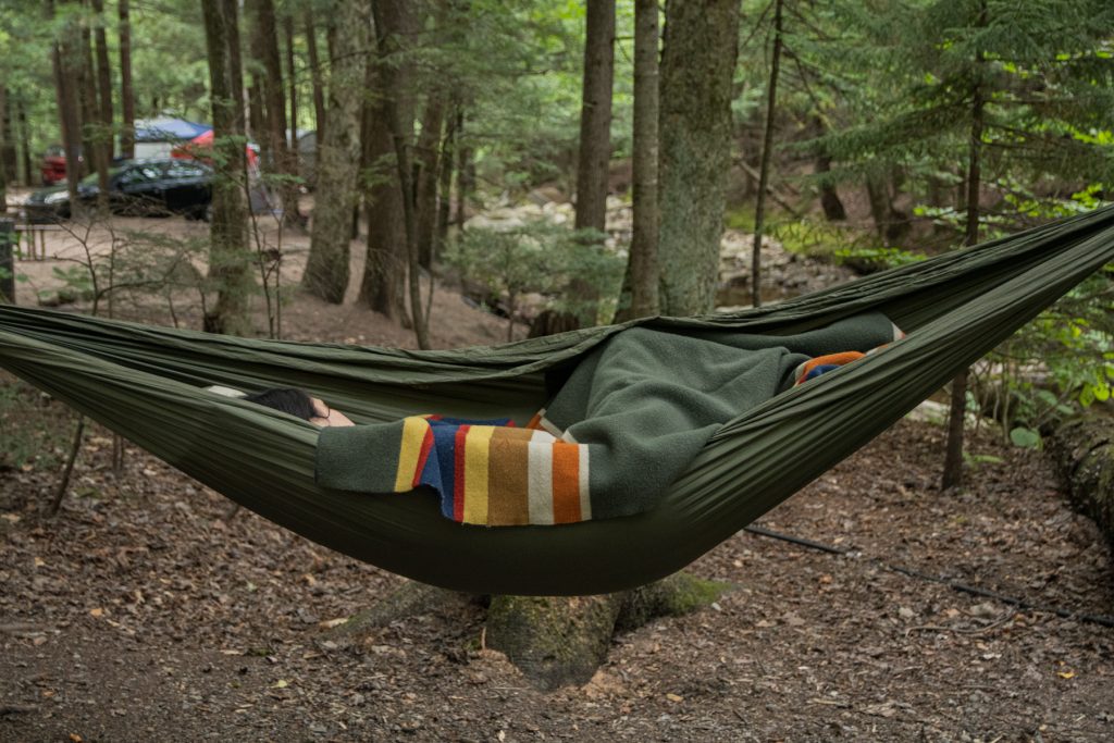 A woman sleeps in a green ENO hammock at Lost River Valley Campground in North Woodstock, New Hampshire. The campground is located in White Mountain National Park.