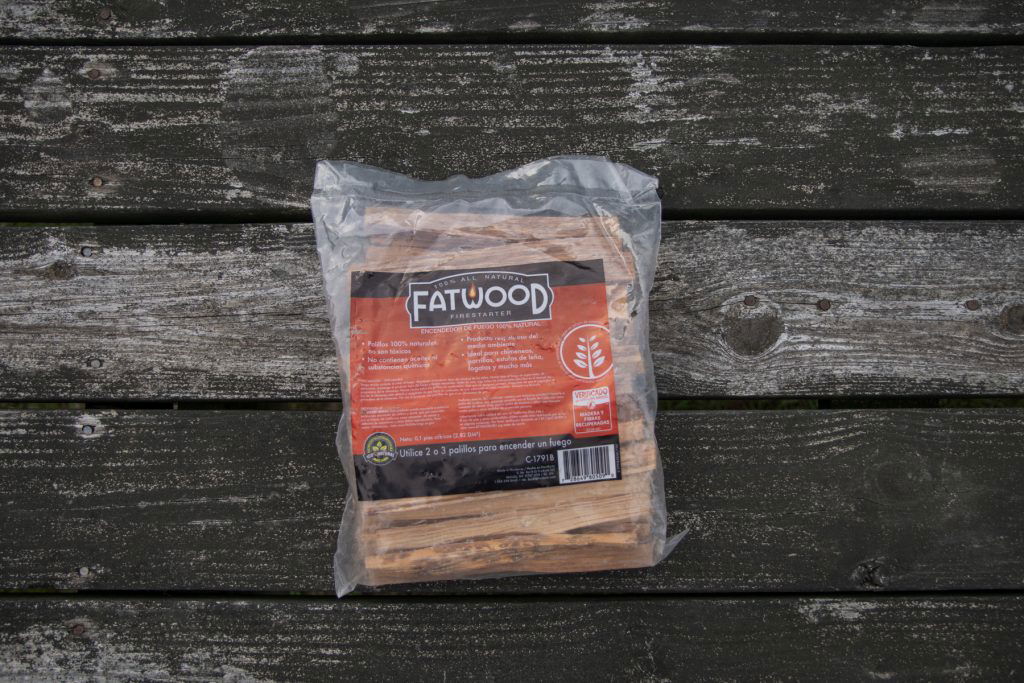 A bag of Fatwood on top of a wooden picnic table.