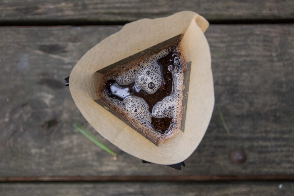 Top down shot of MiiR's Pourigami with hot water and ground coffee shown within a coffee filter.