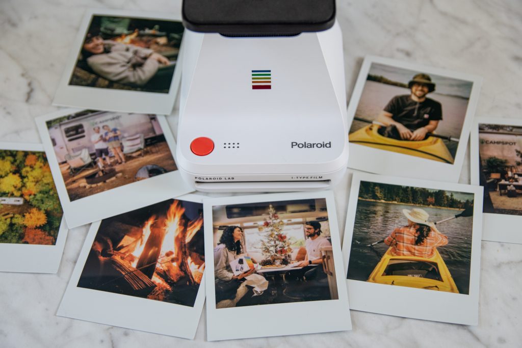 Polaroid Instant Lab Printer with Polaroid camping images on top of a marble table top.