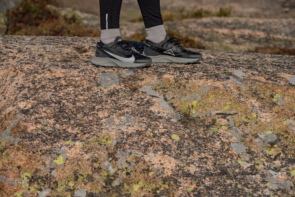 Black Nike trail running shoes on top of a boulder.