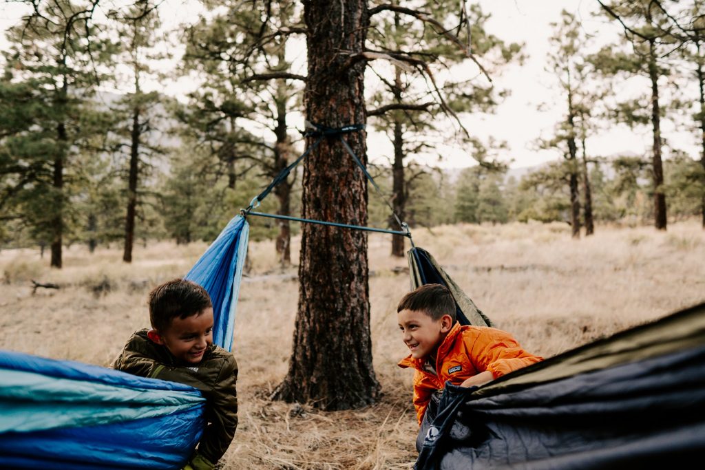 Two children in two ENO hammocks swinging from a tree.