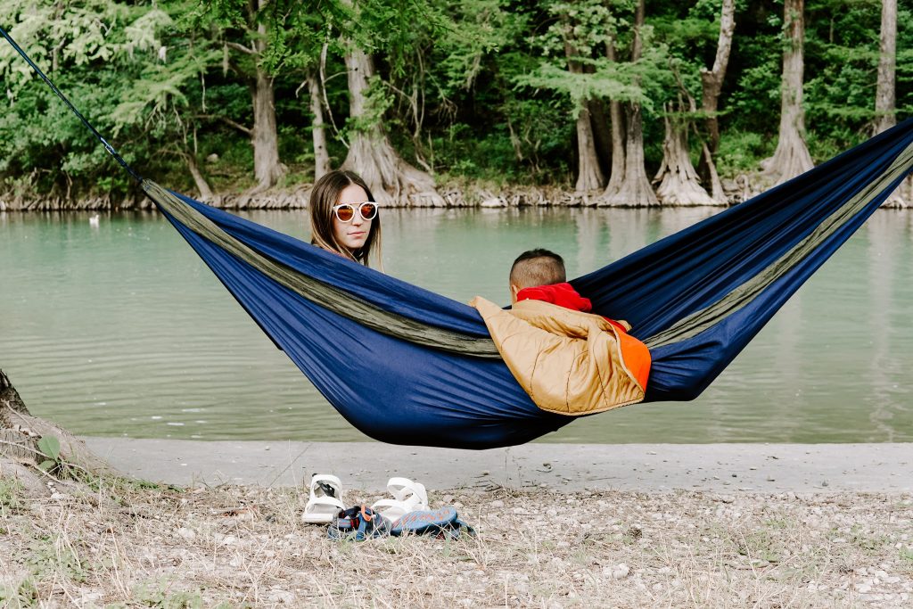 Woman and child on an ENO hammock next to a river.