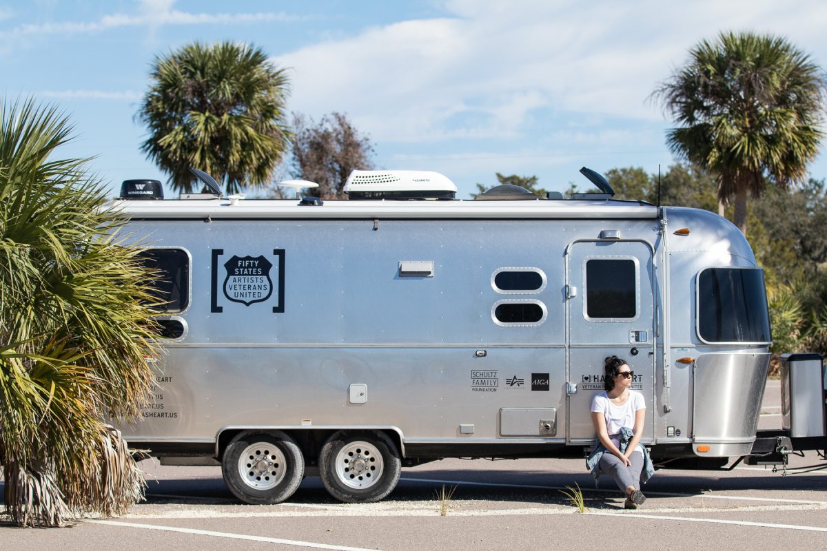 A woman sits on the steps of an Airstream trailer parked at a Wal-Mart parking lot. Wallydocking is staying in a Wal-Mart parking lot overnight.