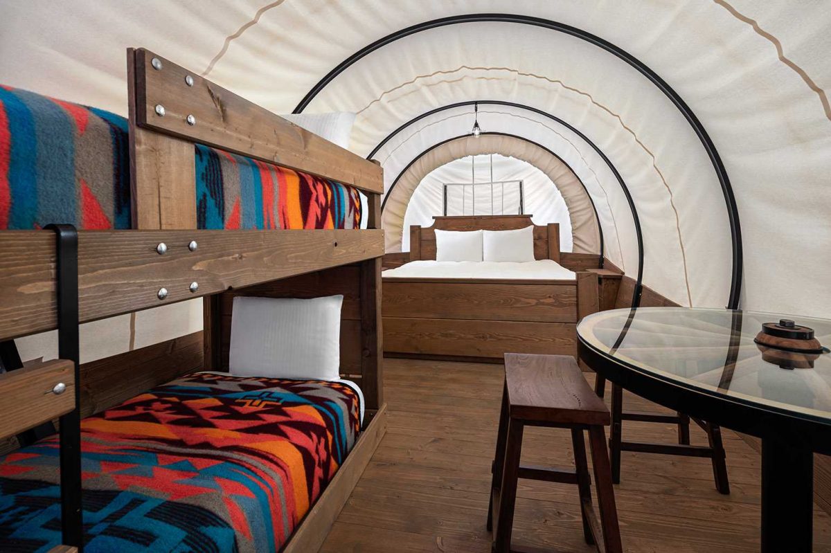 Interior of Conestoga Wagon with Queen bed and twin bunk beds.