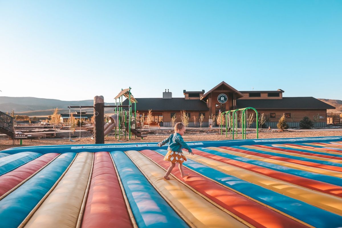 Little kid walking on jumping pillow with playground in background