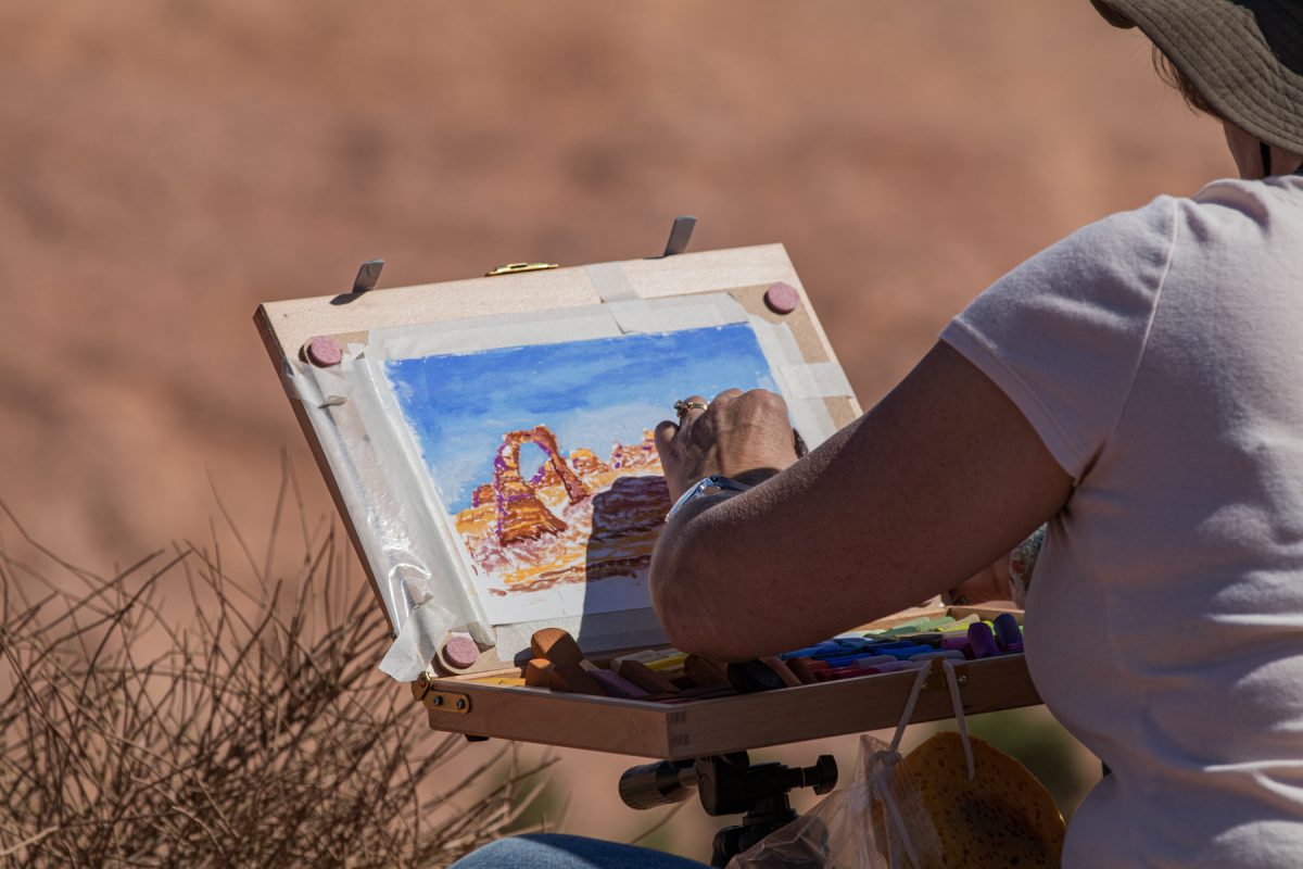 A woman uses pastels to depict the famous Delicate Arch in Arches National Park in Moab, Utah.