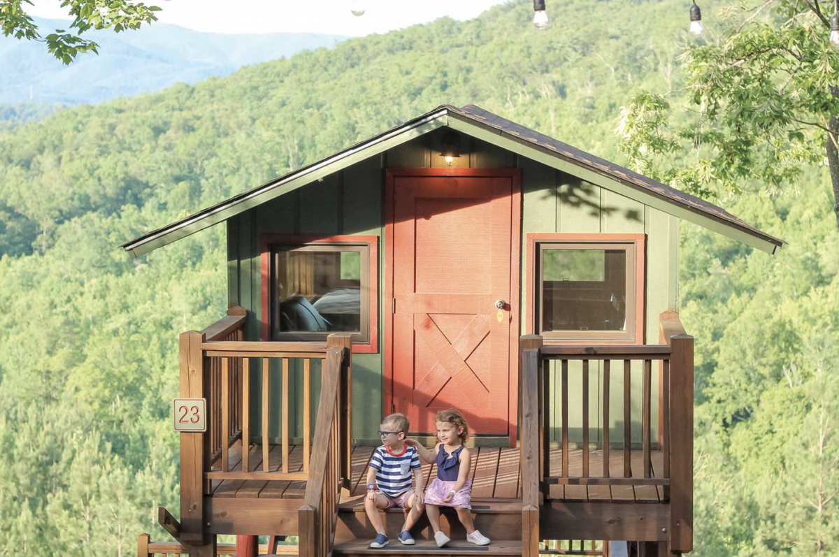 Two children sitting in a tree top cabin with trees in the background at Golden Valley.