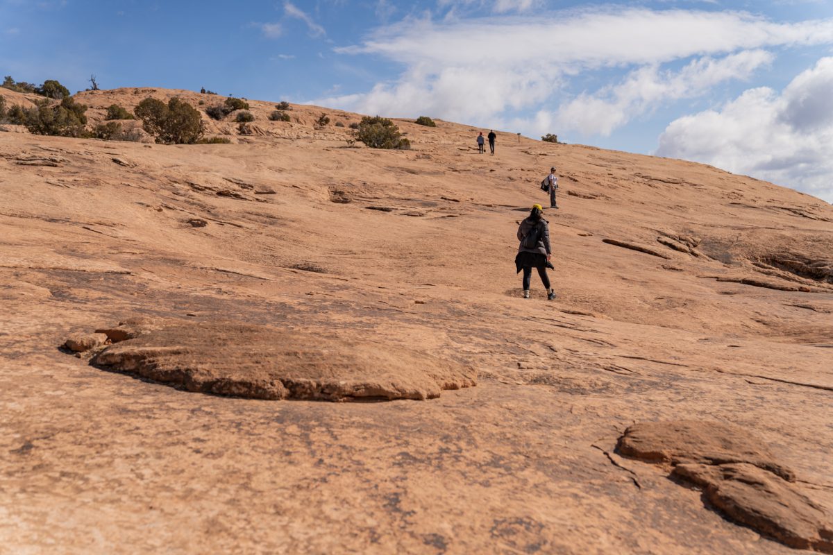 Hikers go up the steep slickrock incline on the Delicate Arch trail in Arches National Park in Moab, Utah.