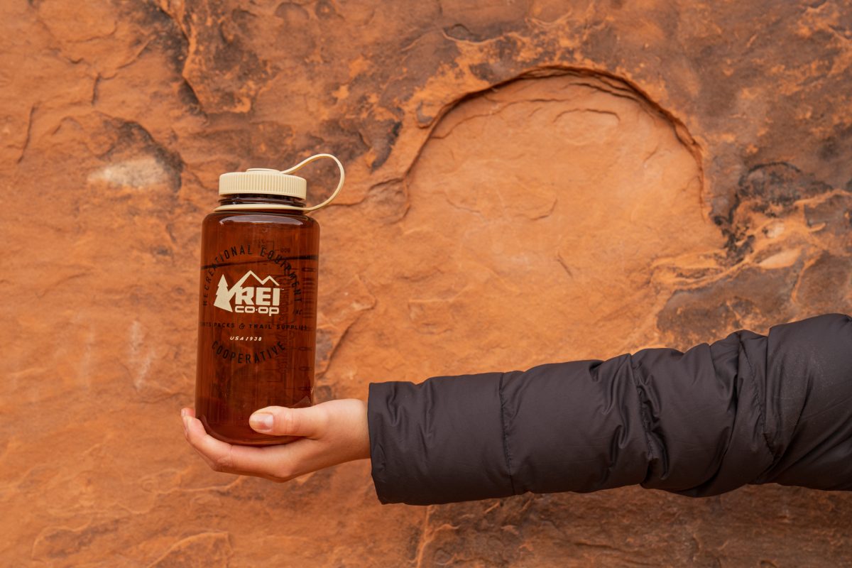 A hiker holds up their water bottle while hiking the Devils Garden Trail in Arches National Park in Moab, Utah.