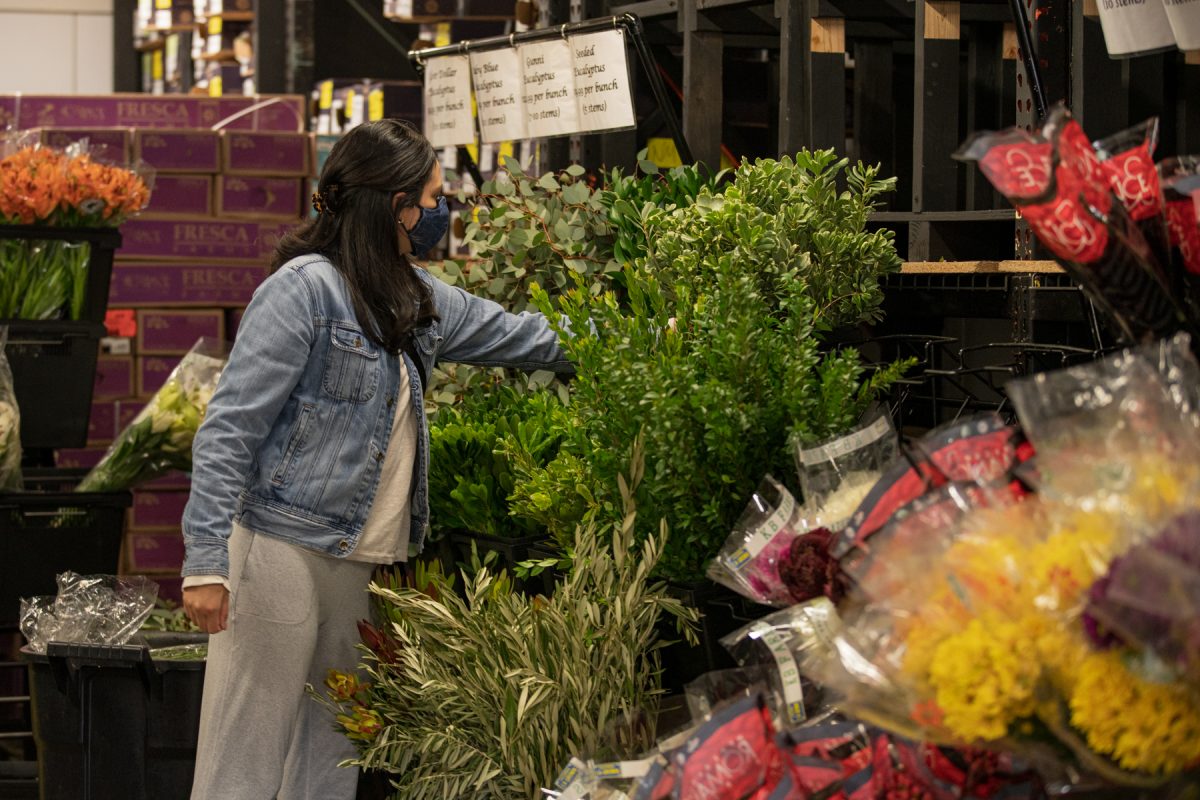 A woman looks through greenery at the Albuquerque Flower Market in Albuquerque, New Mexico.