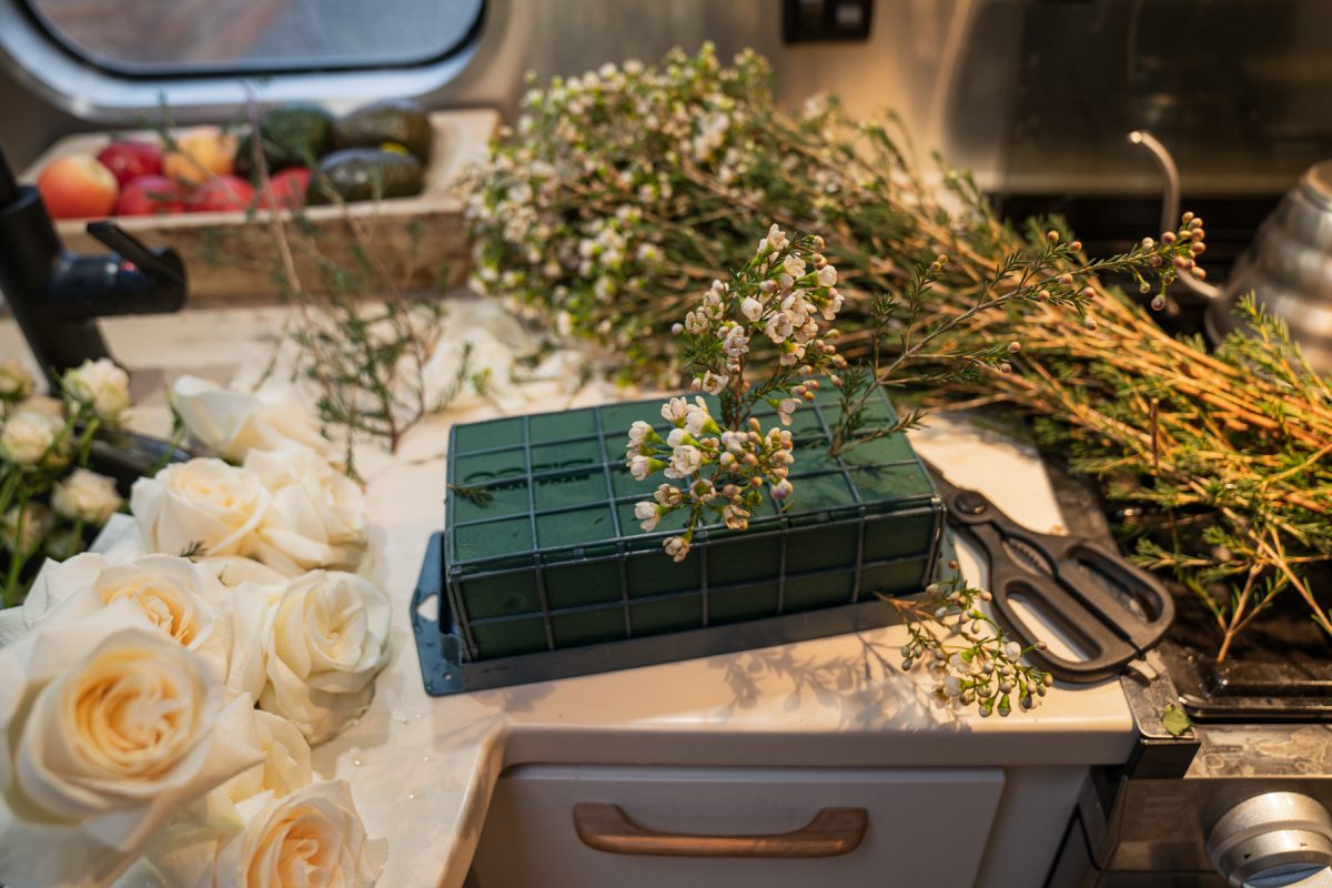 Shorter stems of wax flowers are poked into soaked floral foam.