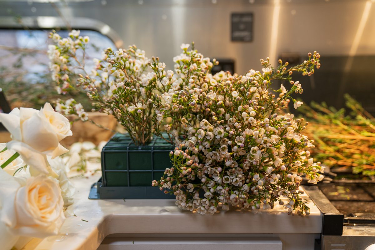 A soaked floral foam is partially covered in wax flower stems. The foam structure is sitting on top of an RV countertop.