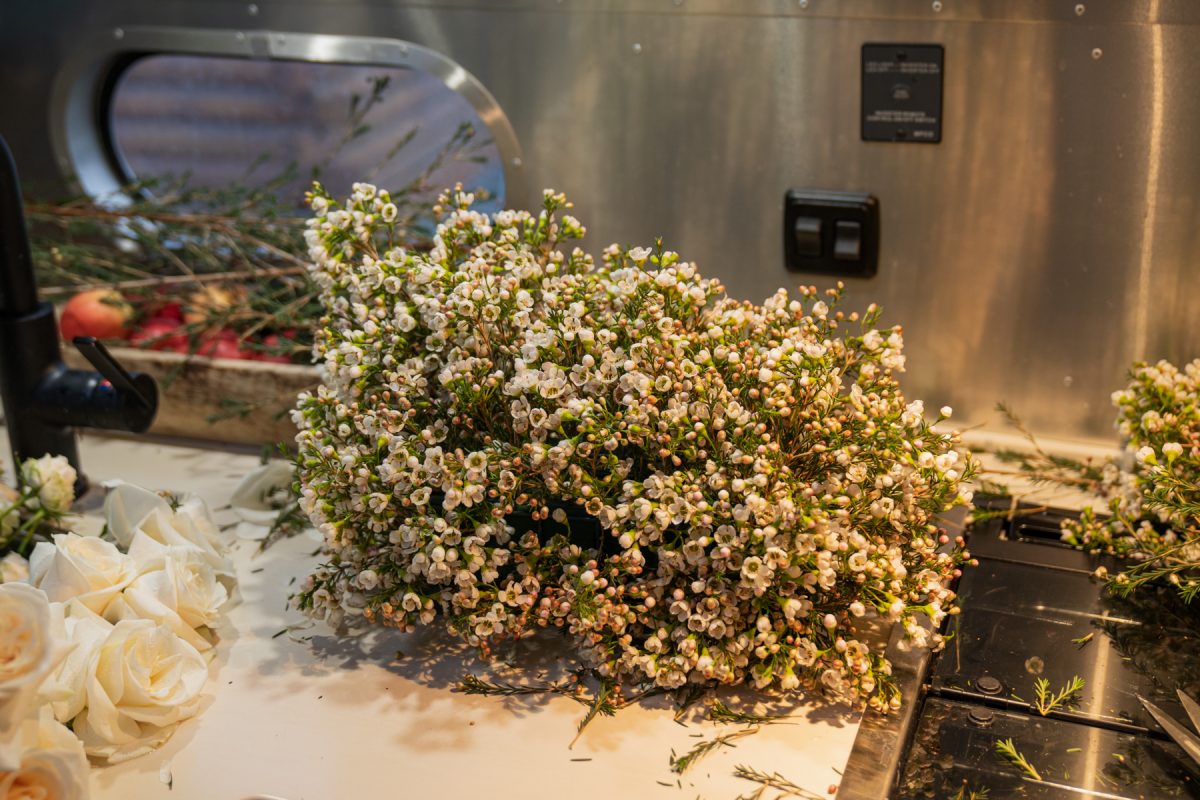 A floral foam is completely covered in wax flower stems and is sitting on top of an RV countertop.