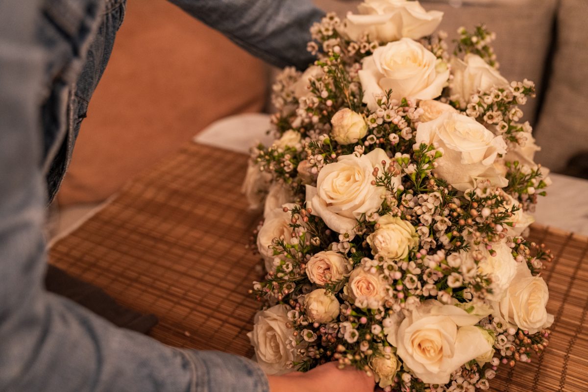 A person sets down a floral arrangement of roses and wax flowers on top of a table within an Airstream RV.