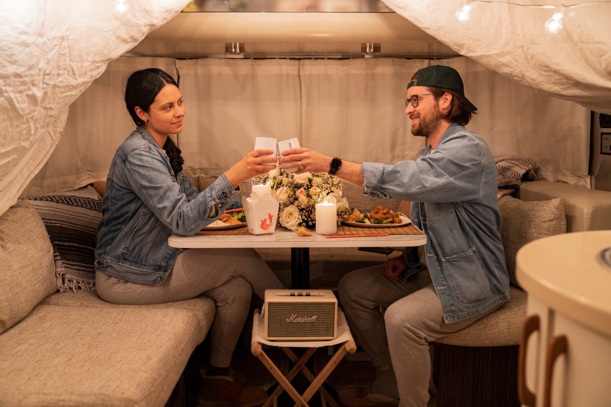 A couple cheers while celebrating Valentine's Day with a date night inside their RV trailer. 