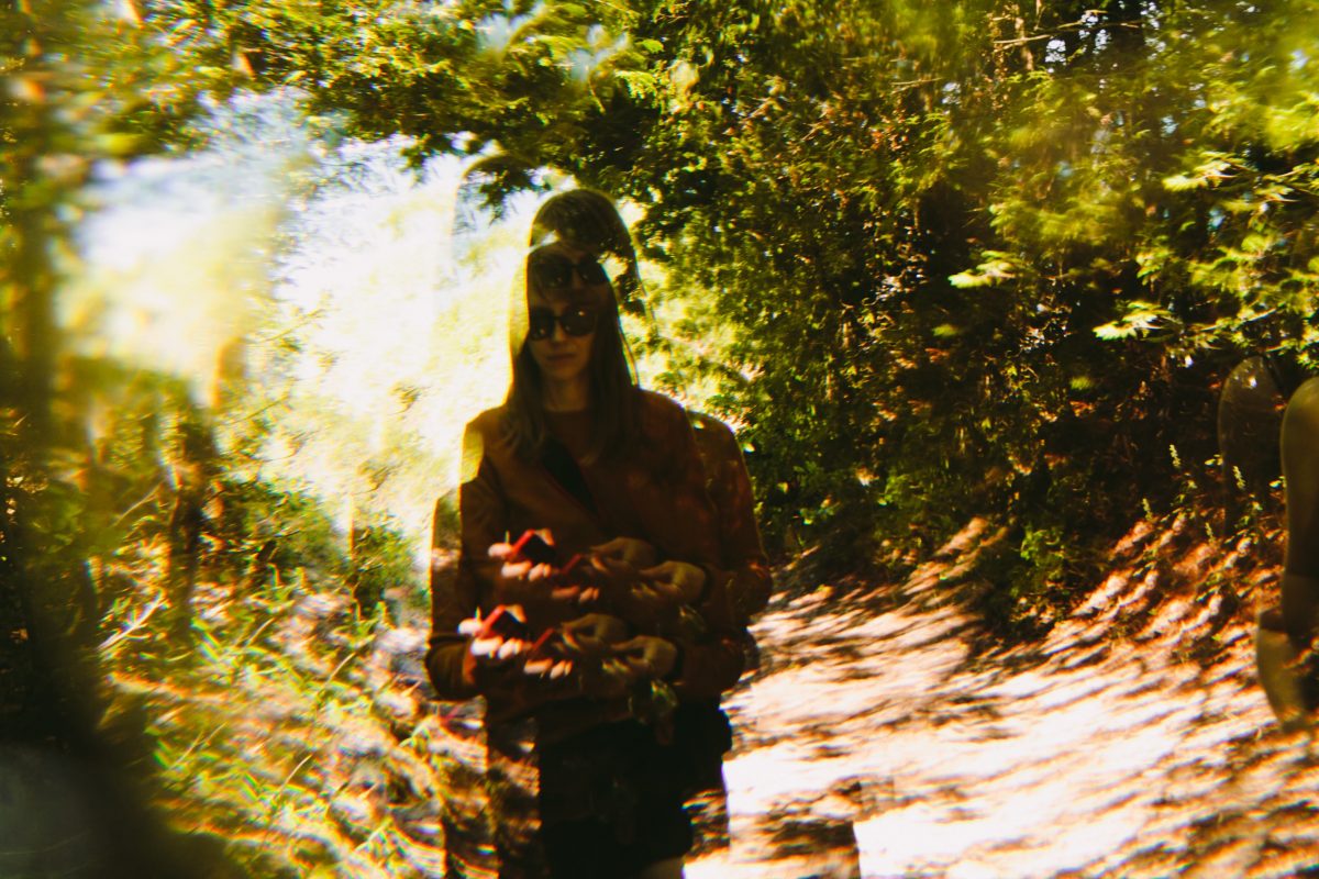 A trippy image of a woman hiking down a path in the woods.