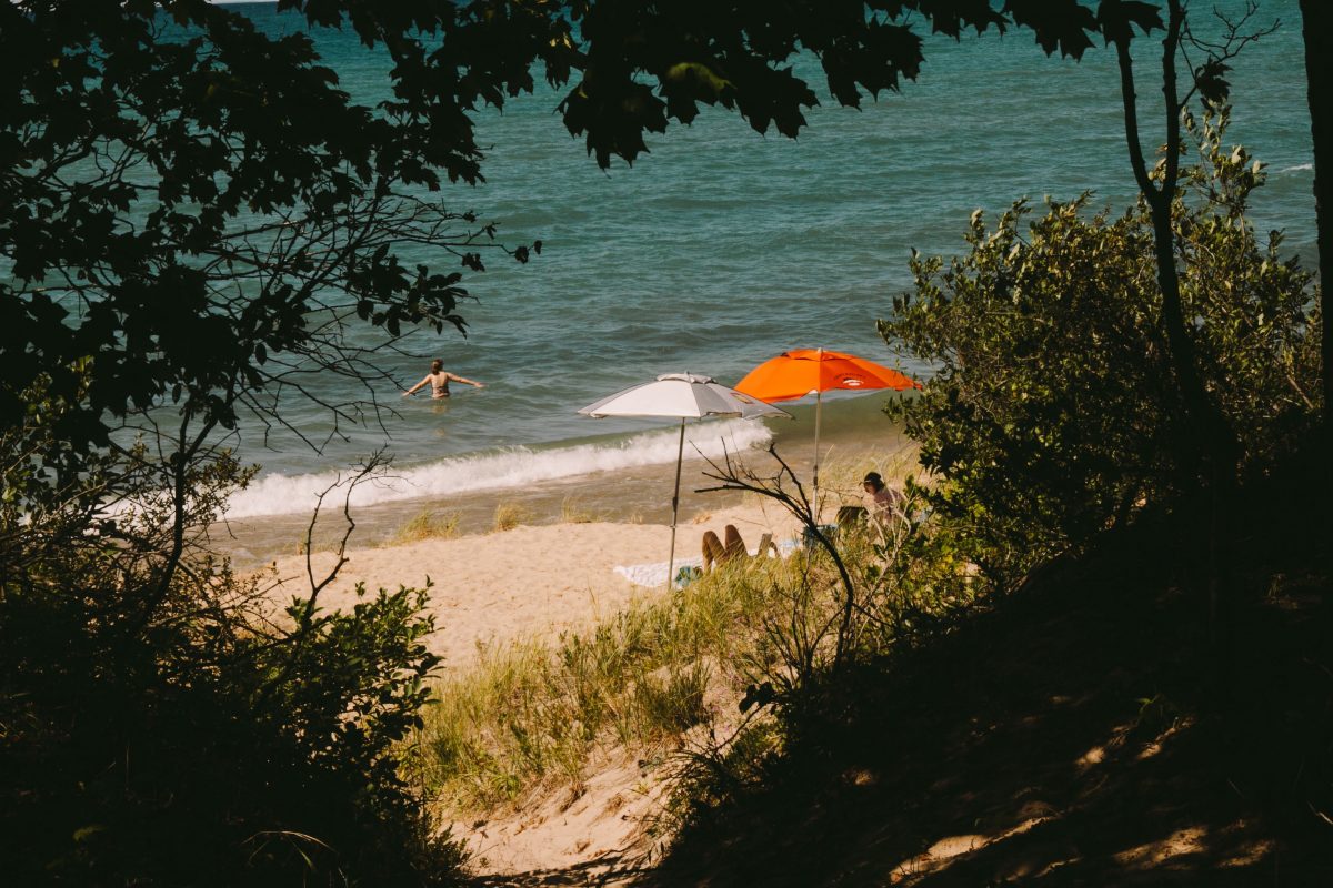 Two umbrellas on the beach at Fisherman's Island State Park with a woman swimming in the water.