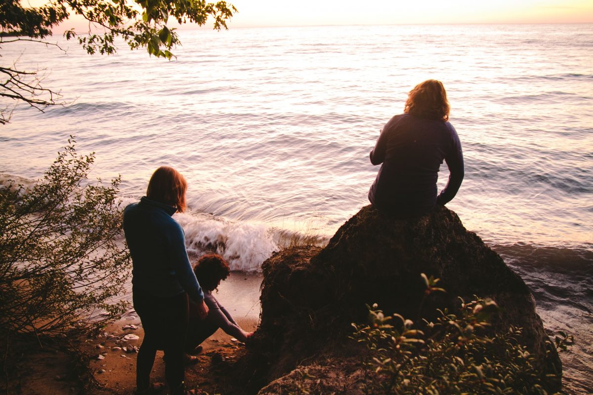 Three women look out to the sun setting on Lake Michigan on Fisherman's Island State Park in Northern Michigan.