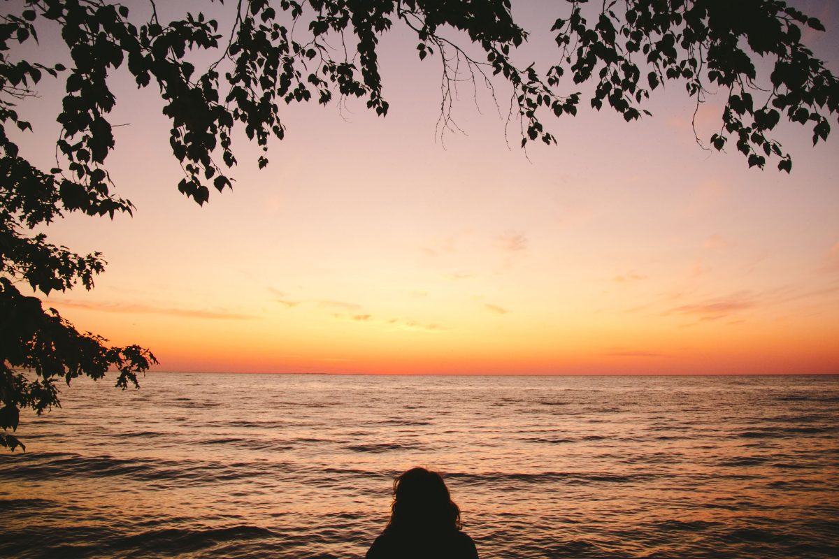 A woman looks out to the sunset on Lake Michigan at Fisherman's Island State Park in Northern Michigan.