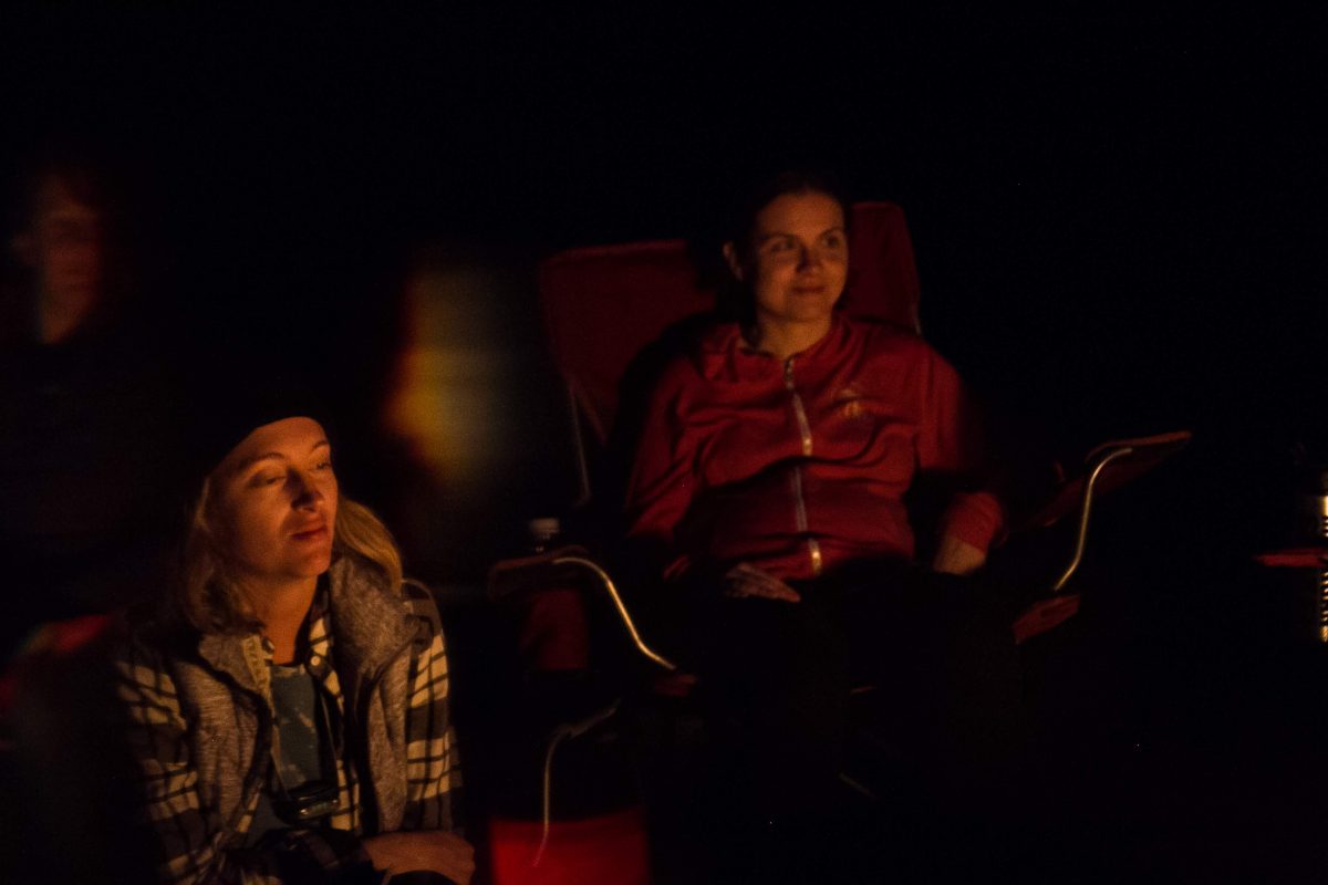 Two women look onto the campfire at their campsite at Fisherman's Island State Park in Northern Michigan.