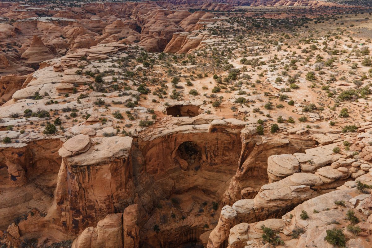 An aerial view of the Gemini Bridges in Moab, Utah. It appears as if there is a hole in the ground.