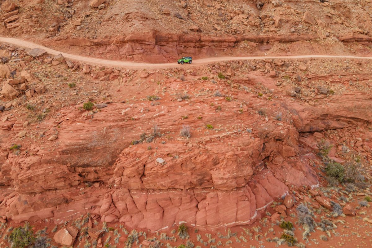 A green jeep rides along the edge of the Gemini Bridges OHV trial in Moab, Utah.