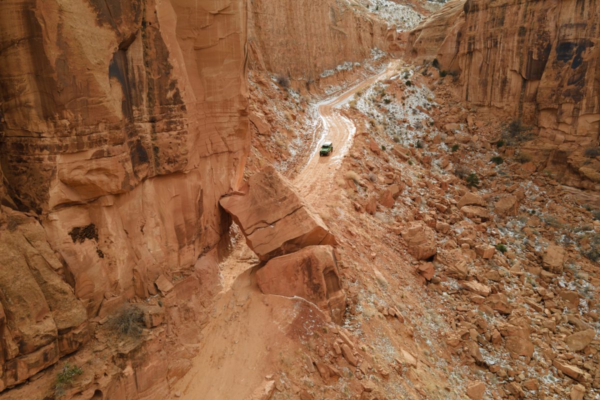 A jeep goes down the Long Canyon OHV trail in Moab, Utah, approaching a giant boulder.