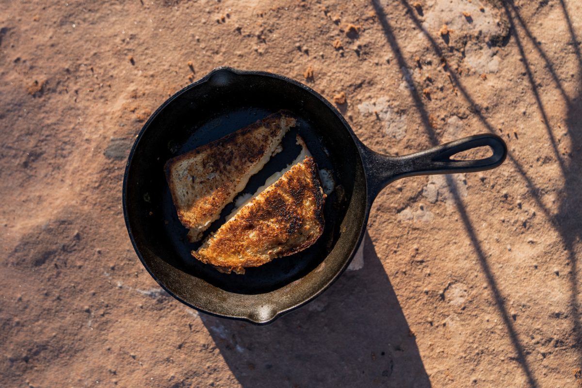 A grilled cheese cut in half, sitting in a cast-iron pan.