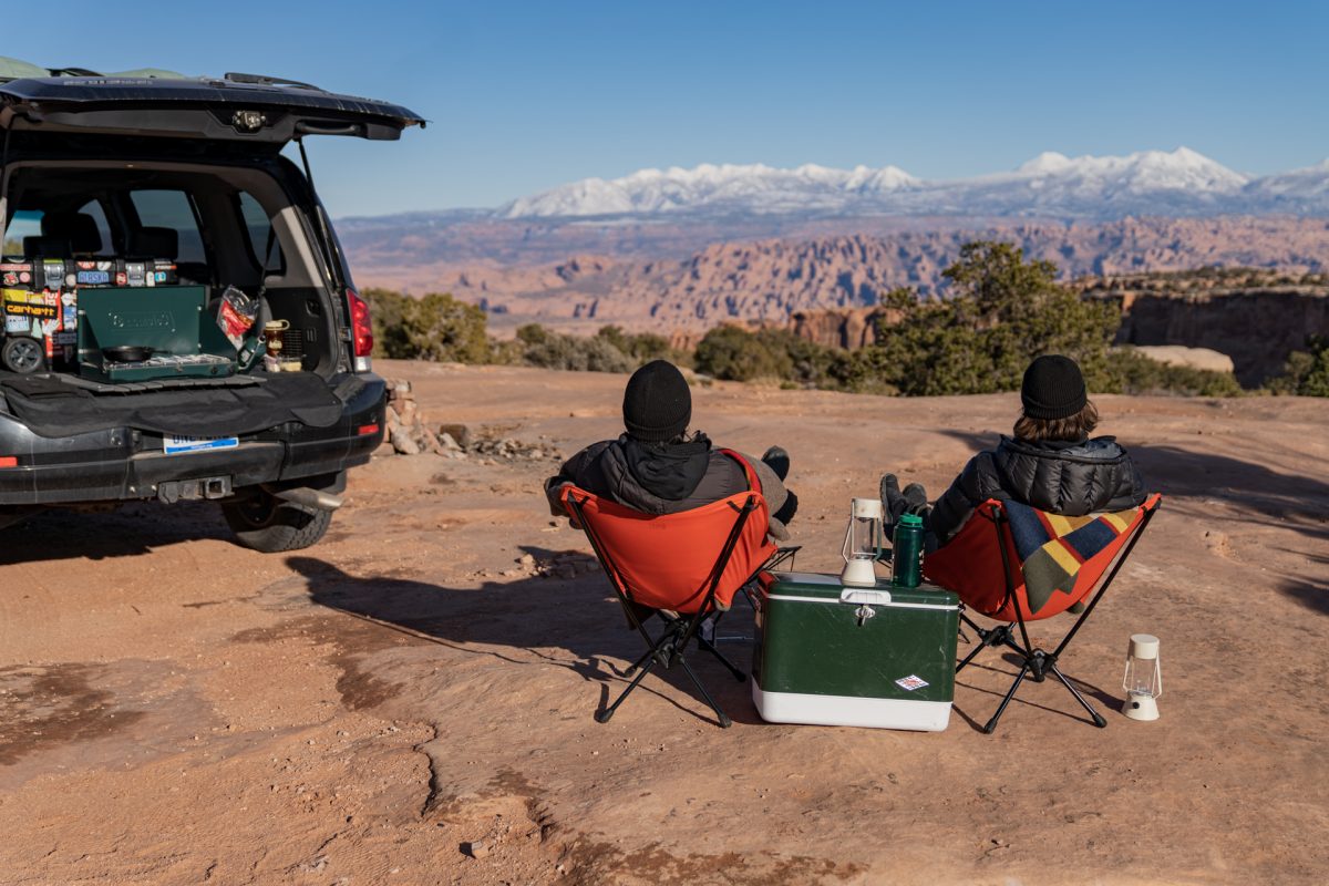 Two people sit in REI camp chairs while looking out to the La Sal Mountains near Moab, Utah.