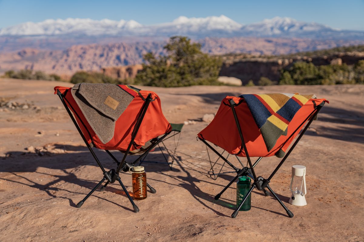 Orange REI camp chairs with Pendleton blankets sitting on top of them, facing toward the La Sal Mountains near Moab, Utah.