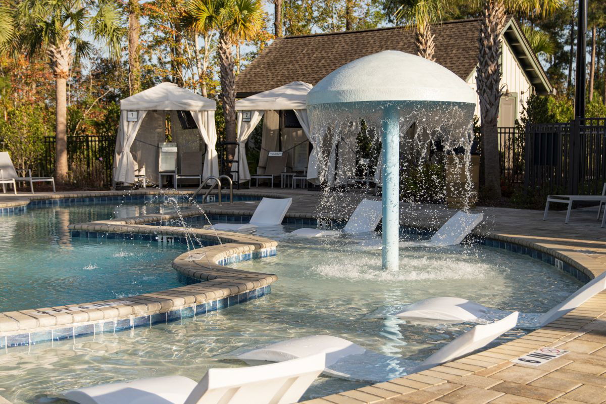 Pool with cabana surrounded by palm trees at Carolina Pines RV Resort