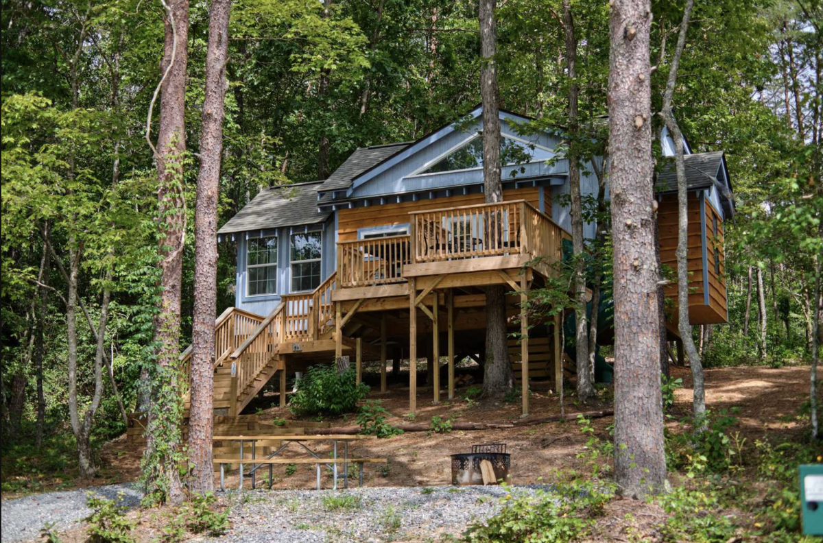 Family treehouse nestled in the woods with a fire pit and picnic table