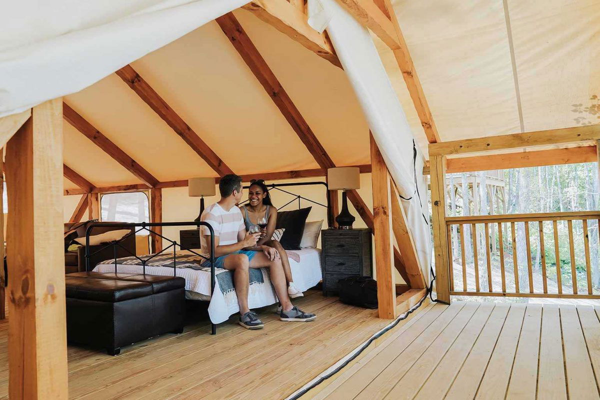 Glamping tent with couple holding wine glasses at Golden Valley