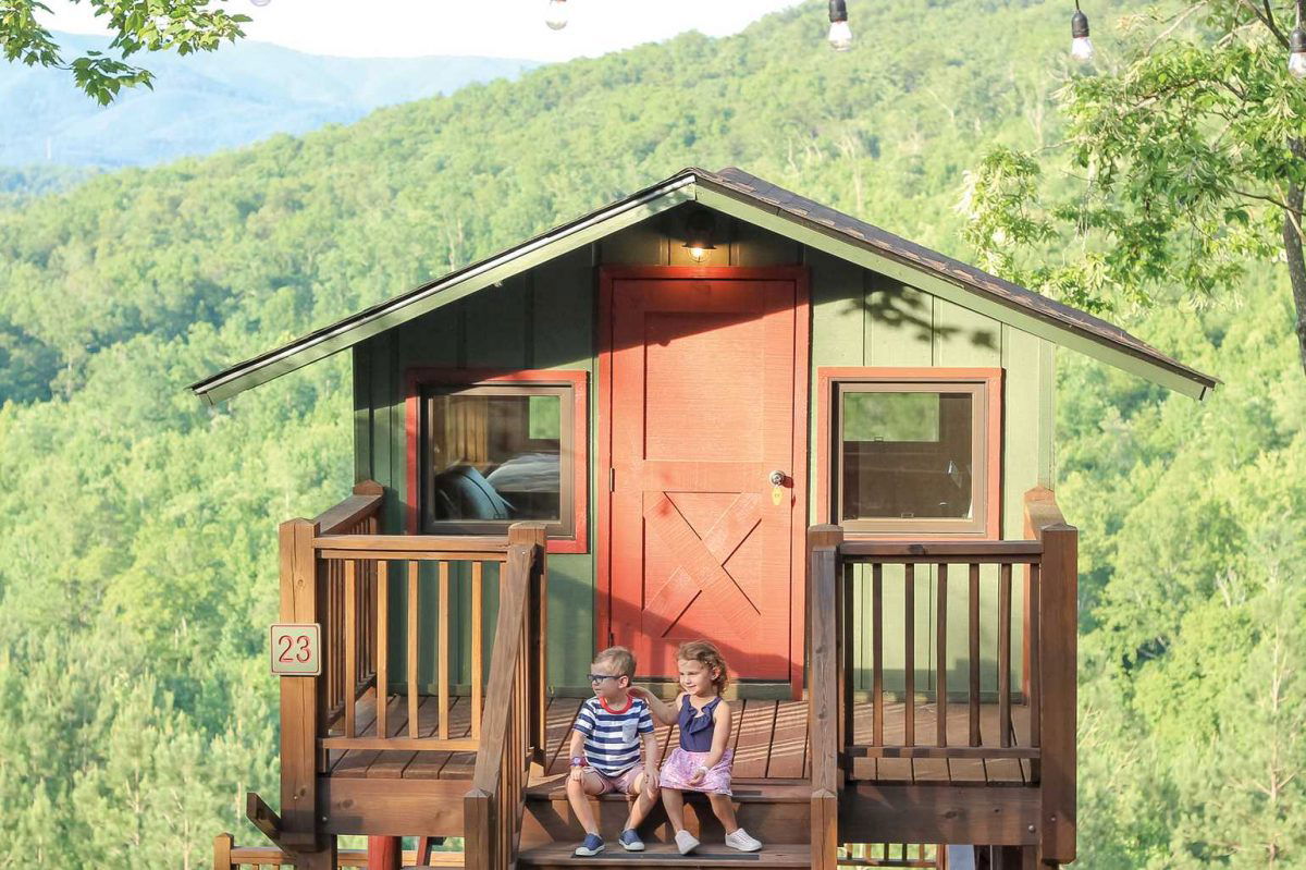 Kids sitting in front of a treehouse at Golden Valley 