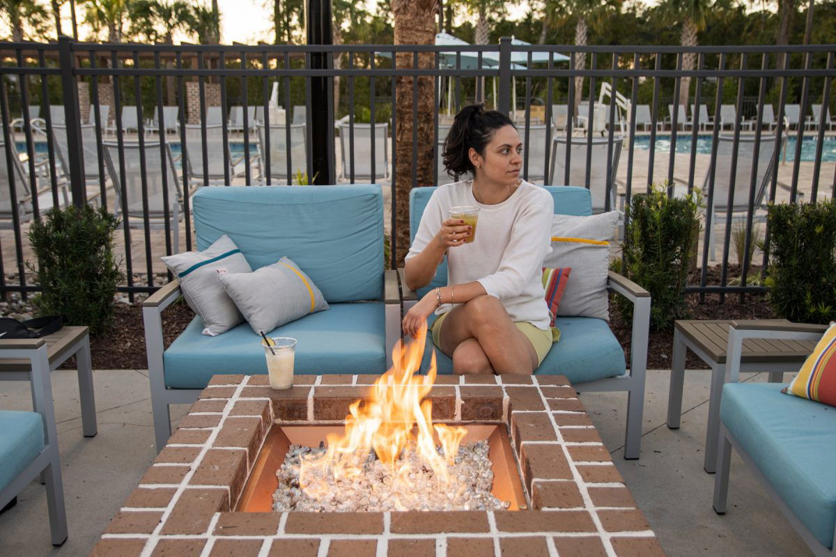 Campspot Ambassador, Kendra lounging outside by a fire at Carolina Pines.