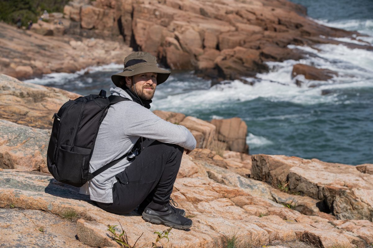 A man sits along the jagged rocks at Acadia National Park in Maine.