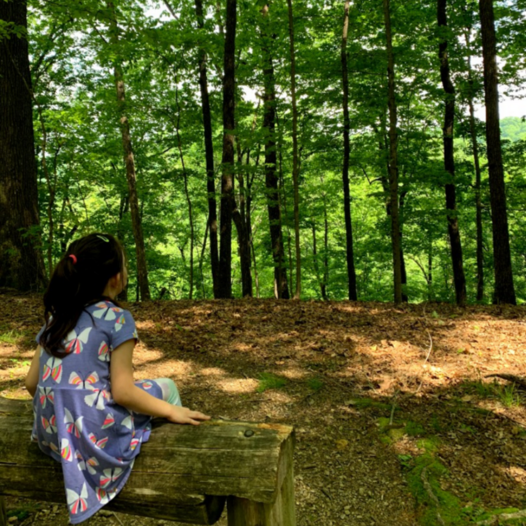 Girl sitting on bench enjoying the woods.