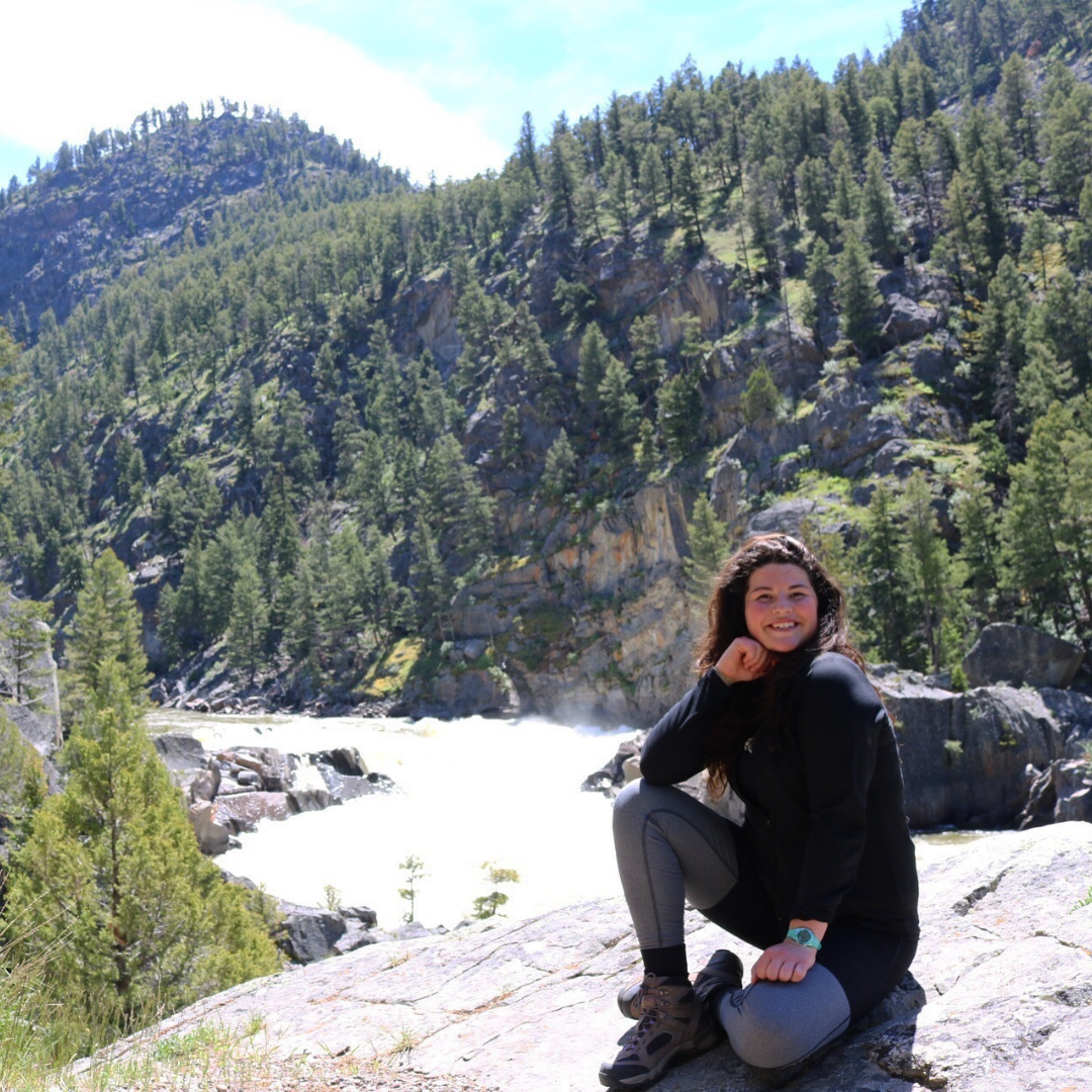 Campspot employee enjoying the great outdoors sitting on a rock.