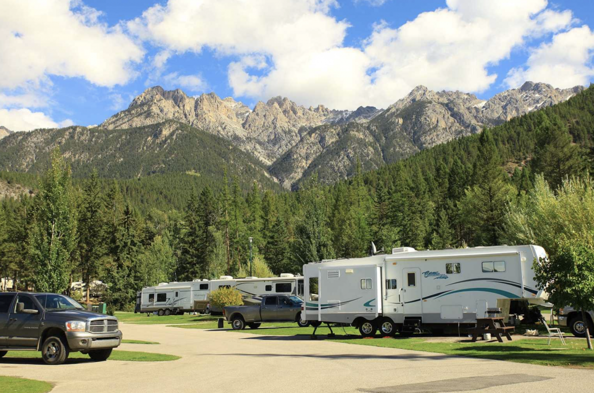 RV parked in front of mountain at campground.