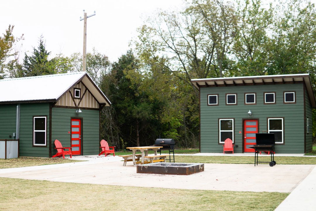 Luxury green cabins with red doors and a fire pit at Hidden Grove RV Resort in Texas.